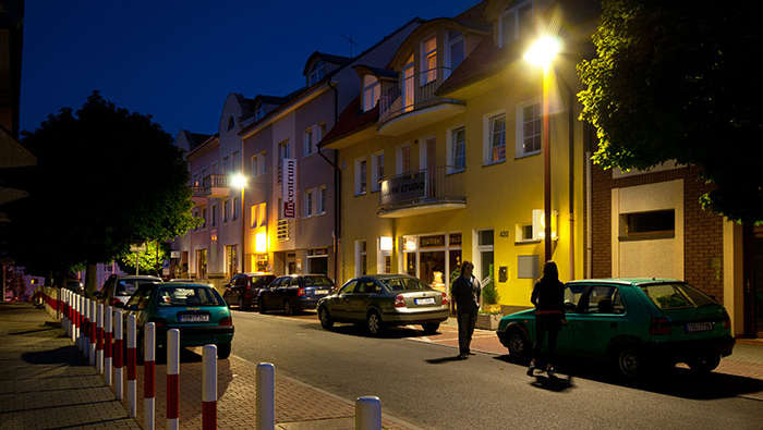 People are walking in the street at the night under Philips street lighting