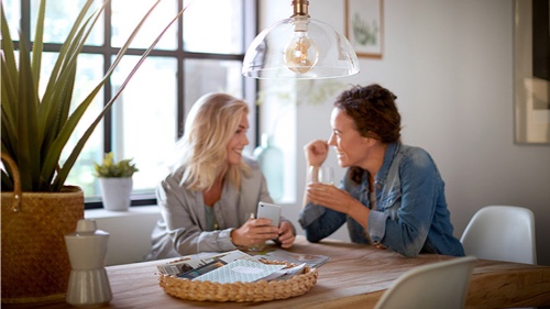 Kaksi naista juttelee kotona Philips lampun alla