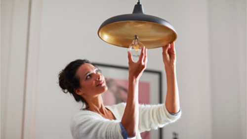 Nainen ruuvaa kuluttaja- hehkulamppua kotona